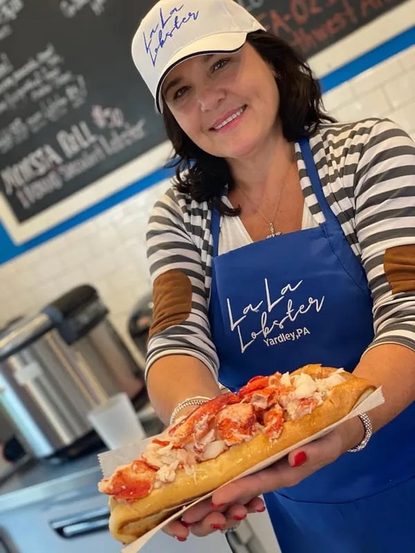 The owner of La La Lobster, Nicole, holding out a lobster roll.
